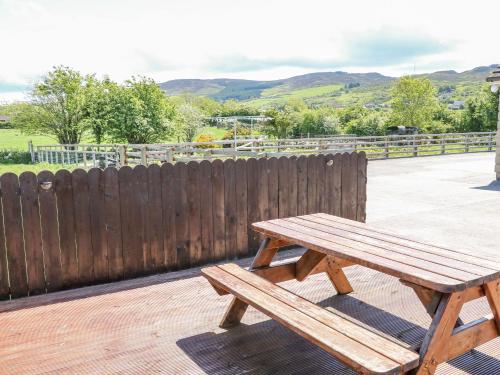 a wooden bench sitting on a deck with a fence at Willow Tree Farm House in Newry