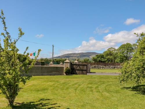 a grassy yard with a fence and mountains in the background at Willow Tree Farm House in Newry