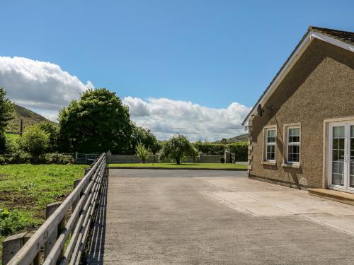 a building with a fence next to a driveway at Willow Tree Farm House in Newry