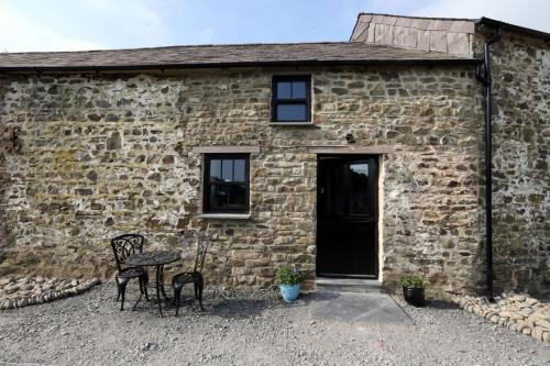 a stone building with two chairs and a table in front of it at Snuggle hot tub Dolgoy in Blaencelyn