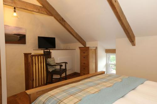 a bedroom with a bed and a chair and a television at Snuggle hot tub Dolgoy in Blaencelyn