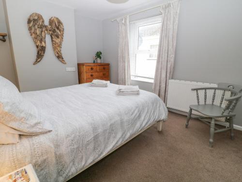 a bedroom with a bed and a chair and a window at 6 Milton Place in Bideford