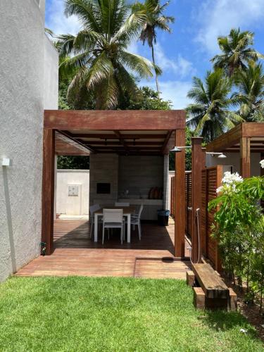 un cortile con un patio in legno con un tavolo di Casa de alto padrão em Antunes - Maragogi a Maragogi