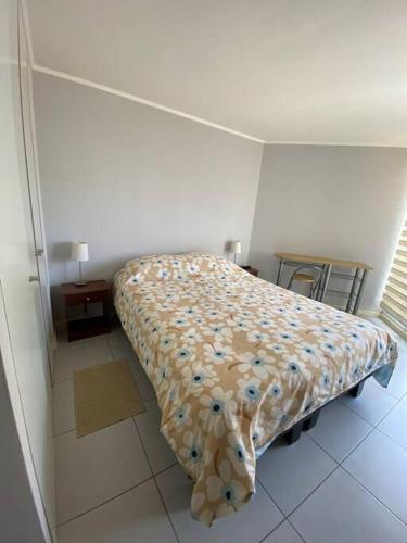 a bedroom with a bed with a floral bedspread at Descanso y Aire Fresco en Los Molles in Los Molles
