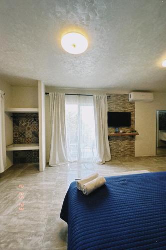 a bedroom with a blue bed and a large window at Hotel Awazul Bacalar in Bacalar