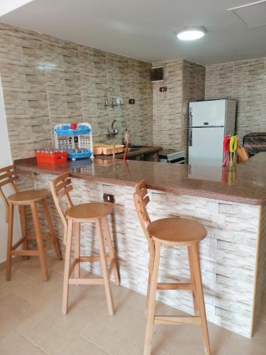 a kitchen with three bar stools and a refrigerator at شالية بقرية بالميرا in Ain Sokhna