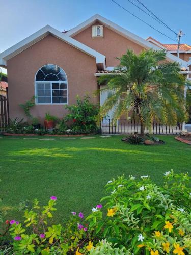 una casa con un jardín con flores delante en Caribbean Estates, 10 mins from the Beach, Beautiful Gated Community, en Portmore