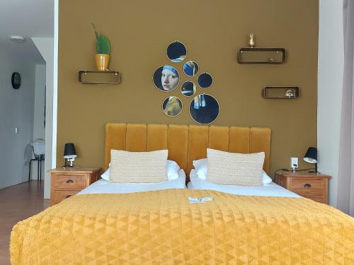 a bedroom with a bed with a yellow blanket and plates on the wall at Prins Appartementen in Egmond aan Zee