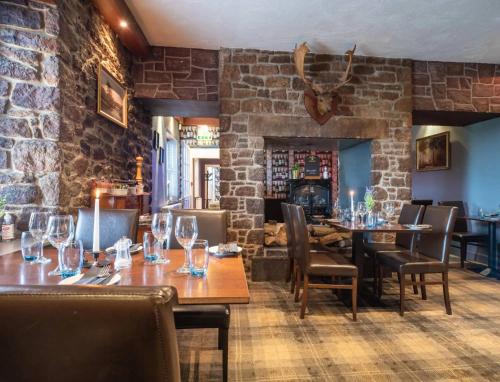 a restaurant with wooden tables and chairs and a brick wall at The Castle Inn in Dirleton