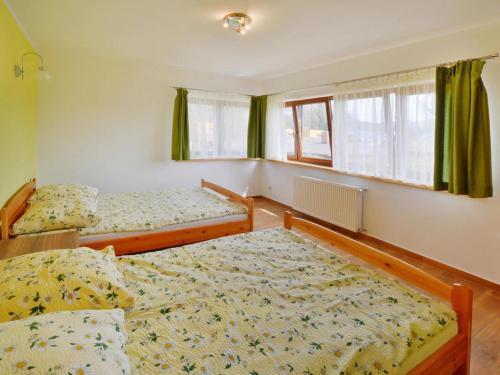 2 camas en una habitación con cortinas verdes en Comfortable holiday home with a nice garden, close to the sea, Sarbinowo, en Sarbinowo