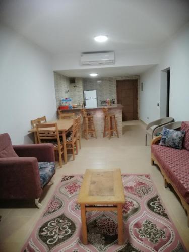 a living room with couches and a table and a kitchen at شالية بقرية بالميرا in Ain Sokhna
