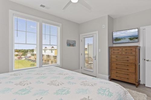 a bedroom with a bed and a dresser and windows at Isle of Dreams in Emerald Isle