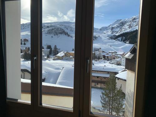 a window with a view of a snow covered mountain at Heimelige Ferienwohnung mit Sicht in die Bergwelt in Bivio