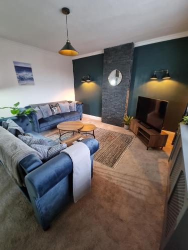 uma sala de estar com um sofá azul e uma televisão em The View Sandbach em Sandbach