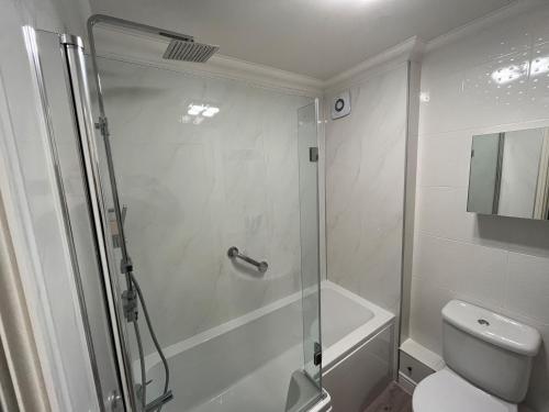 a white bathroom with a shower and a toilet at 4 Victoria Court in Sheringham