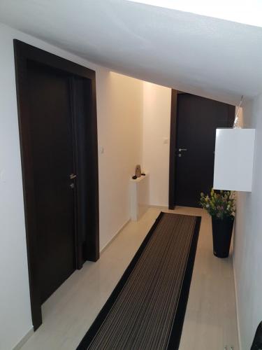 a hallway with two black doors and a rug at Gabi Rooms & Studio Apartment in Lozovac