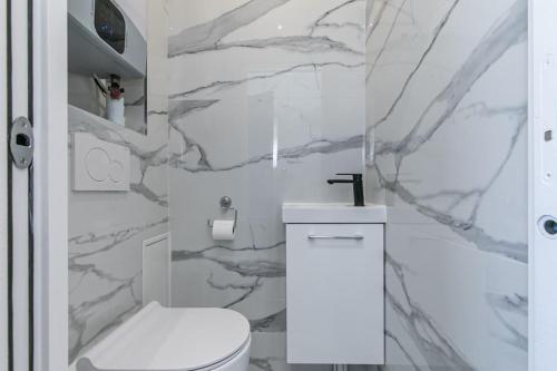 a bathroom with a white toilet and a marble wall at MBA Splendide Appart - Le Raincy - Banlieue Paris in Villemomble