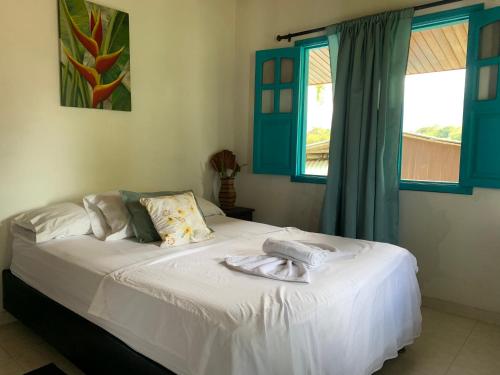 a bedroom with a white bed with blue windows at Posada Villa Margarita in Los Naranjos