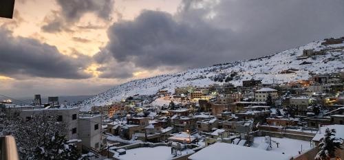 a city covered in snow in front of a mountain at Snow View Suite סוויטת סנו וויו in Majdal Shams