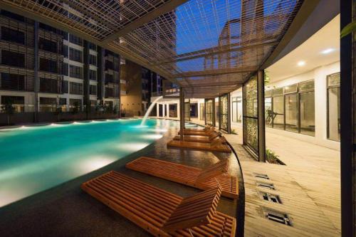 a swimming pool with chaise lounges in a building at Selayang 18 Residences (100mbps Wifi & Netflix) in Batu Caves