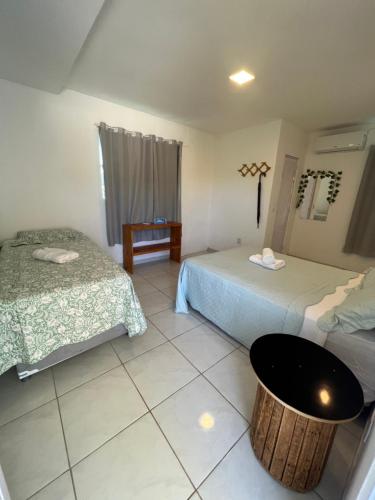 um quarto de hotel com duas camas e uma mesa em POUSADA CENÁRIO IDEAL em Icapuí