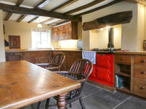 a kitchen with a wooden table and a red stove at Hawkyard's Cottage in Oldham