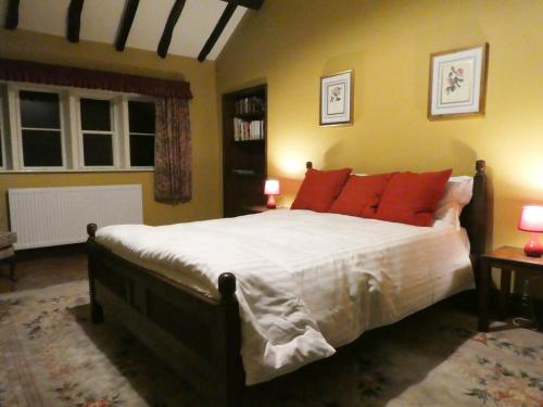 a bedroom with a large bed with orange pillows at Hawkyard's Cottage in Oldham