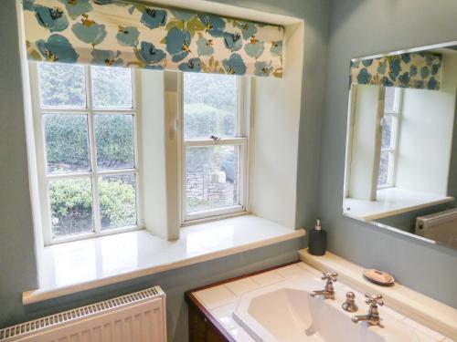 a bathroom with a sink and two windows at Hawkyard's Cottage in Oldham