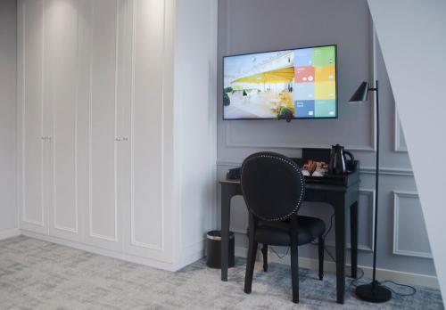 a desk with a chair and a television on a wall at H41 Luxury Suites in Belgrade