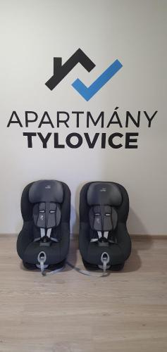 two chairs sitting in front of a company logo at Apartmány Tylovice in Rožnov pod Radhoštěm