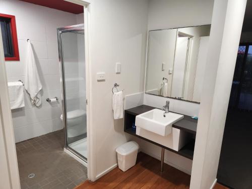 a bathroom with a sink and a shower and a mirror at Serenity Diamond Beach in Diamond Beach