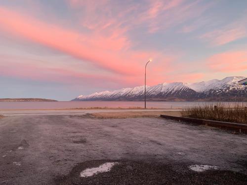 a parking lot with a street light and snow covered mountains at Waterfront Fjord House in Litli-Árskógssandur