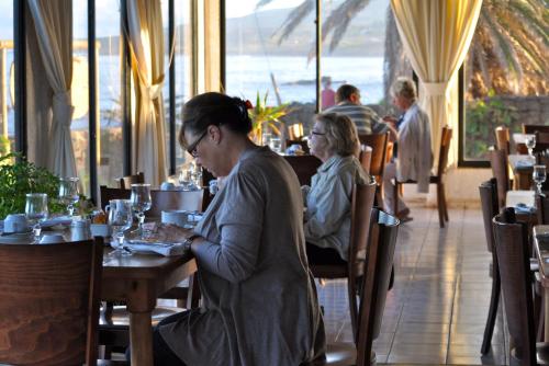 a woman sitting at a table in a restaurant at Taha Tai in Hanga Roa