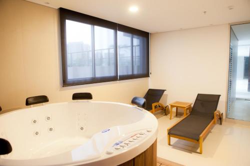 a large bath tub in a room with two chairs at Intercity Brasilia Led Aguas Claras in Brasilia