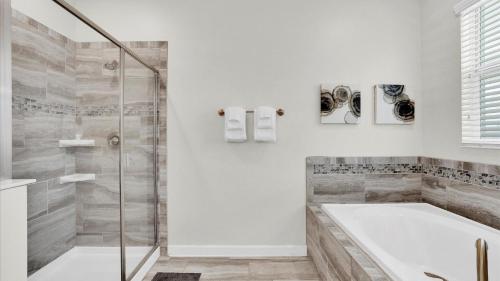 ein weißes Bad mit einer Badewanne und einer Dusche in der Unterkunft Champions Gate Resort - 9 Bed 5 Baths VILLA in Davenport