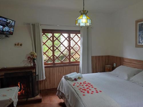 a bedroom with a bed and a fireplace and a window at Pousada Alpenblumen in Monte Verde