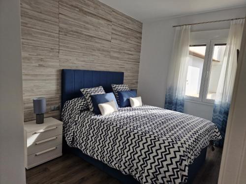 een slaapkamer met een blauw en wit bed en een raam bij La Teresita in Torrox Costa