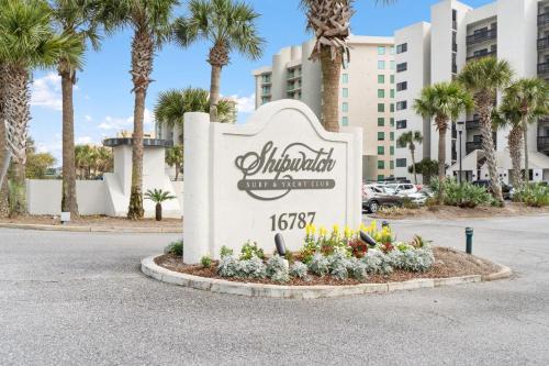 a sign for the entrance to a resort with palm trees at Shipwatch B101 in Perdido Key