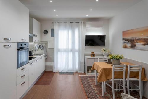 una cucina con mobili bianchi e un tavolo con sedie di OLIVUZZA TOWER a Palermo