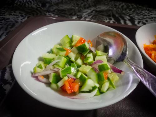 a white bowl of salad with a spoon on a table at Ella Happy View Homestay in Ella