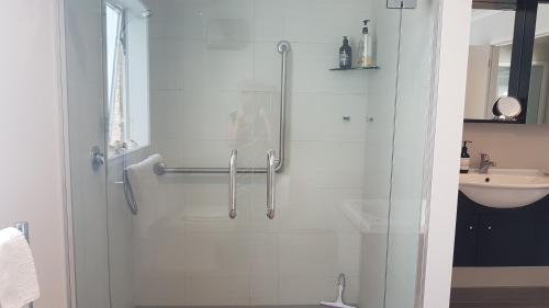 W łazience znajduje się prysznic ze szklanymi drzwiami. w obiekcie Mangawhai Heads apartment w mieście Mangawhai