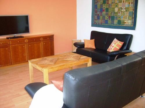 salon z kanapą, stołem i telewizorem w obiekcie Ferienwohnung Ottlinger w mieście Erbach