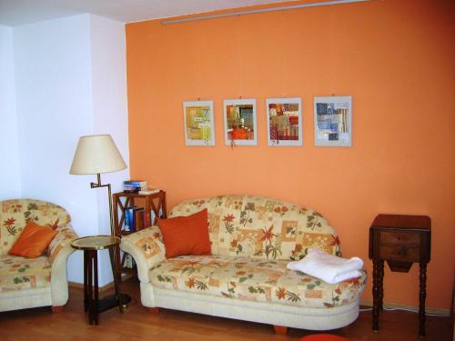 salon z 2 krzesłami i pomarańczową ścianą w obiekcie Ferienwohnung Ottlinger w mieście Erbach