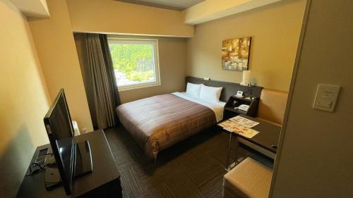 ein Hotelzimmer mit einem Bett und einem Schreibtisch in der Unterkunft Hotel Route-Inn Saiki Ekimae in Saiki