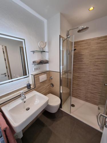 een badkamer met een toilet, een wastafel en een douche bij Strand & Heide - Tolles Schwimmbad in Cuxhaven