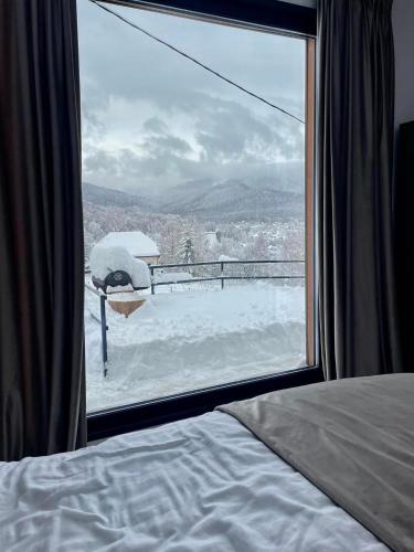 a bedroom window with a view of a snow covered yard at Bella Vista Cheia in Cheia