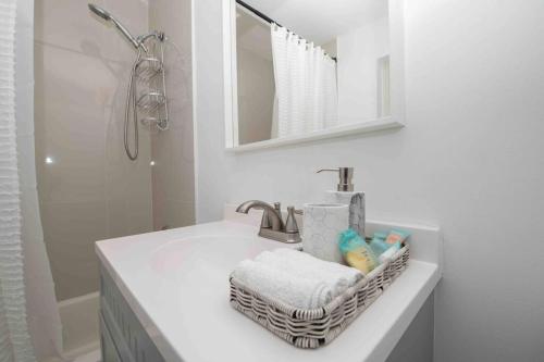 uma casa de banho branca com um lavatório e um espelho em Cozy Blue house blocks from beach with Private Pool, BBQ, Backyard em Deerfield Beach