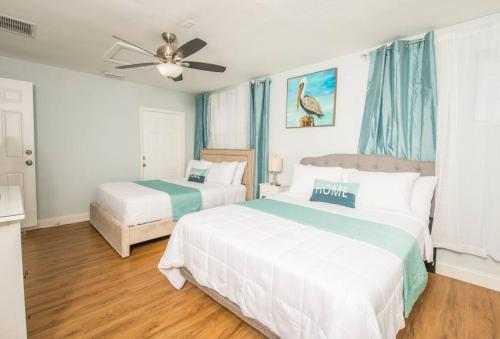 um quarto com 2 camas e uma ventoinha de tecto em Cozy Blue house blocks from beach with Private Pool, BBQ, Backyard em Deerfield Beach