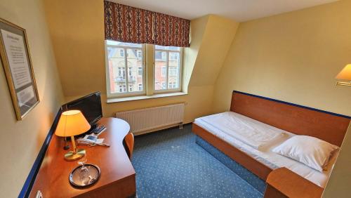 a bedroom with a bed and a desk with a computer at Hotel Amadeus Dresden Neustadt in Dresden