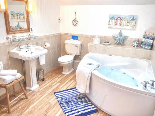 a bathroom with a tub and a toilet and a sink at Anneth Lowen in Pentewan